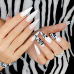 Gel manicure with animalistic pattern and accessories on the hands.