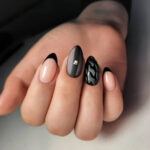 Stylish and strict female manicure with a black French design. Female camouflage manicure with black design and rhinestone.
